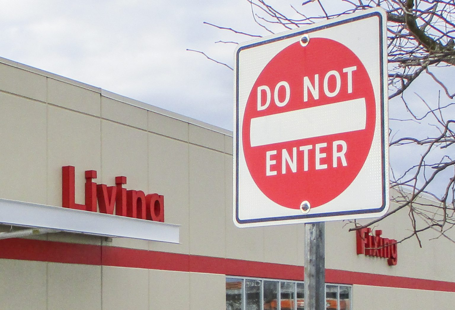 Image shows "Do Not Enter" sign in front of a Canadian Tire store. On the front of the story are two signs that say "Living" and "Fixing"
